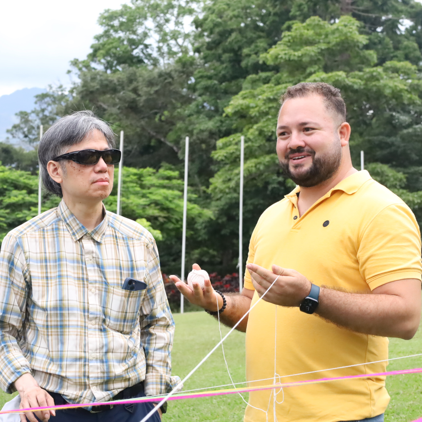 Participants connecting colored threads during an outdoor group activity